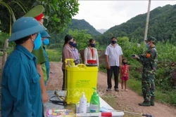 Lực lượng biên phòng tuyên truyền nâng cao nhận thức phòng chống dịch, phát khẩu trang miễn phí, sát khuẩn, kiểm tra y tế (đo thân nhiệt) cho người dân. Ảnh: Xuân Tiến-TTXVN 