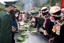 Bộ đội Biên phòng cùng với bà con nhân dân xã Huổi Luông, huyện Phong Thổ (Lai Châu) gói bánh chưng xanh tặng cho hộ nghèo. Ảnh: Đinh Thùy-TTXVN