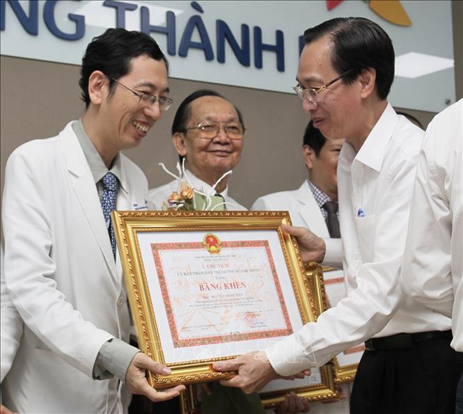 Bác sỹ Nguyễn Minh Tiến (trái), Phó giám đốc Bệnh viện Nhi đồng Thành phố nhận bằng khen. Ảnh: Đinh Hằng - TTXVN Thành phố Hồ Chí Minh: Sức khỏe cặp song sinh dính liền được tách rời tiến triển tốt ảnh 2