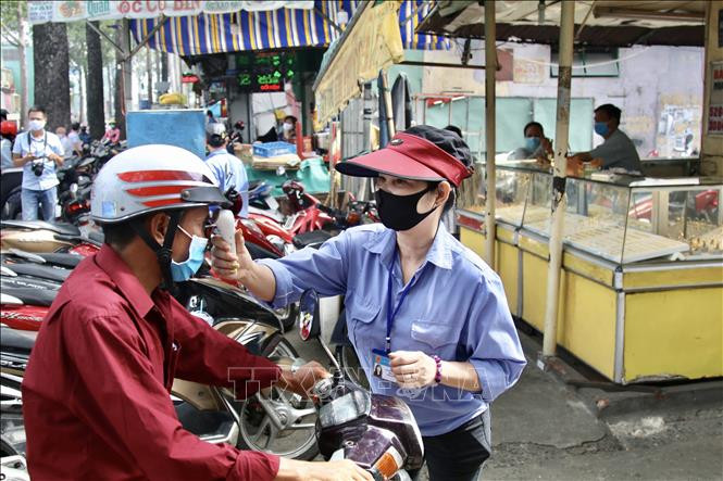 Thực hiện kiểm tra việc đeo khẩu trang và đo thân nhiệt tại chợ Nhật Tảo (quận 10). Ảnh: Hồng Giang - TTXVN Thành phố Hồ Chí Minh tiếp tục rà soát người từng đến Đà Nẵng, khoanh vùng cách ly những trường hợp tiếp xúc với người mắc COVID-19 ảnh 2