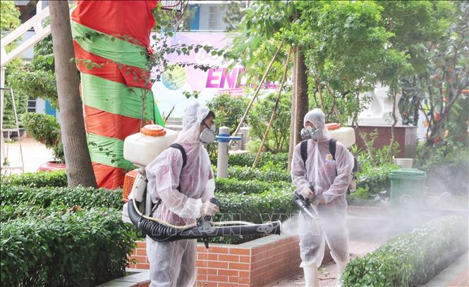 Nhân viên y tế phun thuốc khử khuẩn khu vực sân trường, cây cối, đảm bảo vệ sinh cho khuôn viên trường. Ảnh: Thu Hương - TTXVN Thành phố Hồ Chí Minh xử lý các điểm liên quan đến bệnh nhân COVID-19 ảnh 10