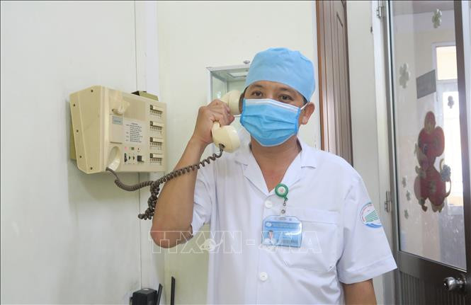 Bác sỹ Nguyễn Thanh Phong, Trưởng Khoa Nhiễm D- Bệnh viện Bệnh Nhiệt đới Thành phố Hồ Chí Minh trao đổi bằng điện thoại với bệnh nhân trong phòng cách ly áp lực âm. Ảnh: Đinh Hằng - TTXVN COVID-19: Chuyện chưa kể về hành trình 65 ngày điều trị cho bệnh nhân 91 ảnh 1