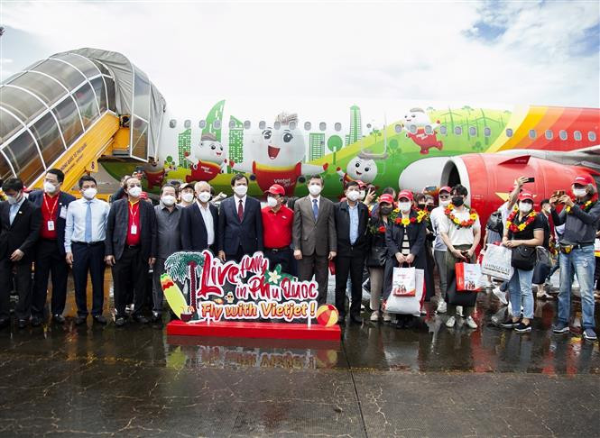 Đại diện lãnh đạo Tổng cục Du lịch, lãnh đạo tỉnh Kiên Giang, Hãng hàng không Vietjet cùng những du khách quốc tế đầu tiên đến du lịch Phú Quốc sau gần hai năm du lịch Việt Nam bị “đóng băng” do dịch COVID-19. Ảnh: Hồng Đạt - TTXVN Kiên Giang đón đoàn du khách quốc tế "hộ chiếu vaccine" đầu tiên đến Phú Quốc ảnh 4