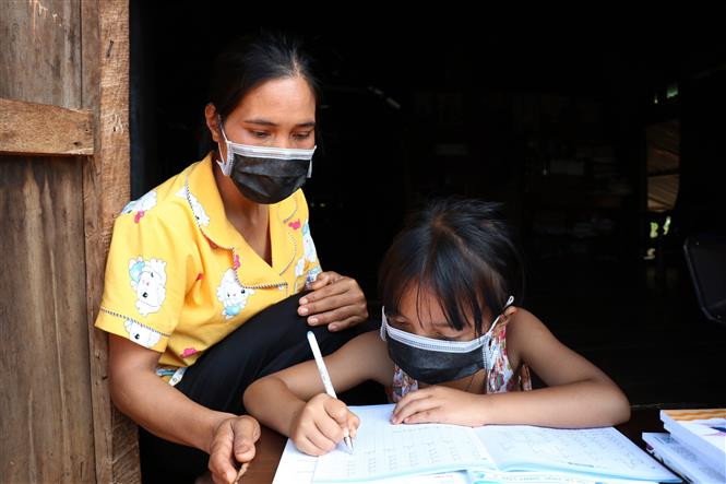 Phụ huynh tại xã Cư Mgar, huyện Cư M'gar (Đắk Lắk) hướng dẫn học sinh học tại nhà khi không có điều kiện học trực tuyến. Ảnh: Tuấn Anh - TTXVN Đắk Lắk hỗ trợ học sinh khó khăn do ảnh hưởng của dịch COVID-19 ảnh 1