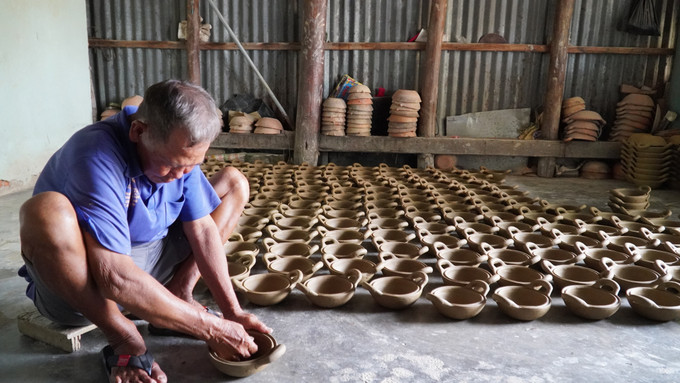 Ông Trần Ngọc Minh ở thị trấn Hòn Đất (Kiên Giang) đang kéo đường chỉ cho nồi đất. Ảnh: Văn Sĩ - TTXVN Người dân Hòn Đất vẫn gắn bó với nghề nắn nồi đất dù thu nhập giảm ảnh 1