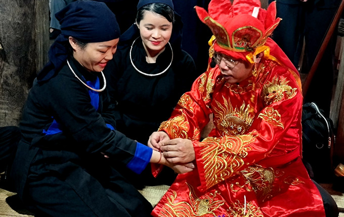 Thầy cúng buộc sợi chỉ đỏ may mắn cho mọi người dự lễ. Ảnh: Hoàng Tâm Đặc sắc lễ cầu an, cầu phúc của đồng bào dân tộc Tày ảnh 8