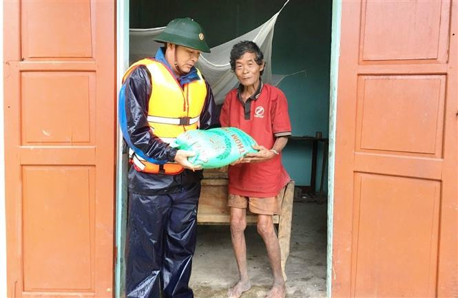 Cán bộ, chiến sỹ Bộ đội Biên phòng Quảng Bình trao tặng các nhu yếu phẩm cho bà con vùng núi, biên giới bị ảnh hưởng do mưa lũ. Ảnh: Võ Dung - TTXVN Sẻ chia khó khăn với người dân vùng lũ tỉnh Quảng Bình ảnh 4