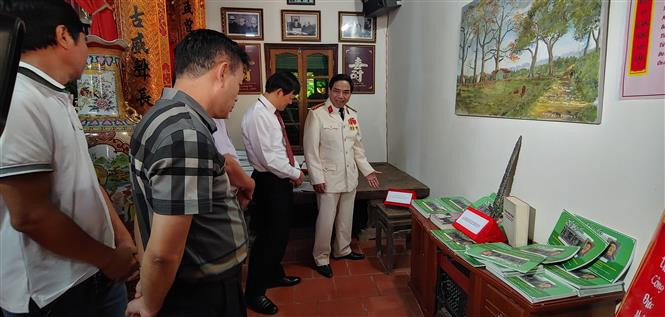 Đại diện gia đình giới thiệu với khách tham quan các hiện vật lịch sử. Ảnh: Nguyễn Cúc - TTXVN Kỷ niệm 66 năm Ngày giải phóng Thủ đô: Khánh thành biển lưu niệm sự kiện cách mạng kháng chiến ảnh 2