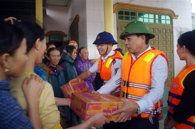 Thượng tá Cao Xuân Quận, Chủ nhiệm Chính trị Bộ tư lệnh Vùng Cảnh sát biển 1 và đồng chí Phan Xuân Khánh, Phó Trưởng ban Thường trực, Ban Dân vận Tỉnh ủy Quảng Bình trao quà cho bà con vùng lũ thị xã Ba Đồn. Ảnh: TTXVN phát Sẻ chia khó khăn với người dân vùng lũ tỉnh Quảng Bình ảnh 1