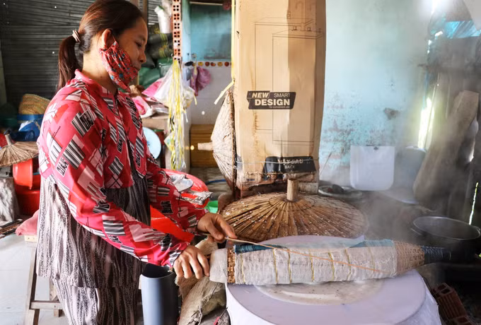 Công đoạn lấy bánh vừa hấp chín ra đòi hỏi sự khéo léo để tránh bánh bị giòn, dễ vỡ. Ảnh: Hữu Chí – TTXVN