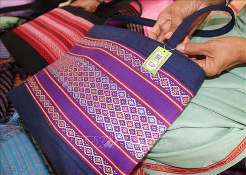 Dán “tem điện tử thông minh” cho sản phẩm thổ cẩm. Ảnh: Nguyễn Thành - TTXVN