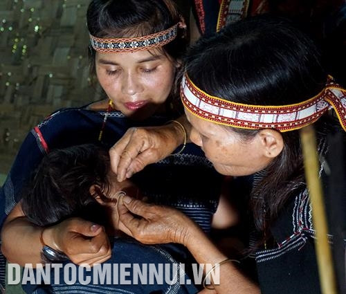 Bà đỡ thực hiện nghi thức thổi tai và xỏ lỗ tai cho đứa trẻ. Ảnh: Hoàng Hải