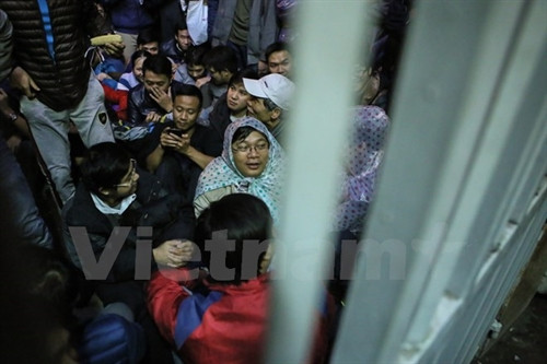 Trời mưa phùn nhưng các phụ huynh quyết tâm bám trụ vì nếu di chuyển sẽ mất ngay chỗ. (Ảnh: Minh Sơn/Vietnam+)