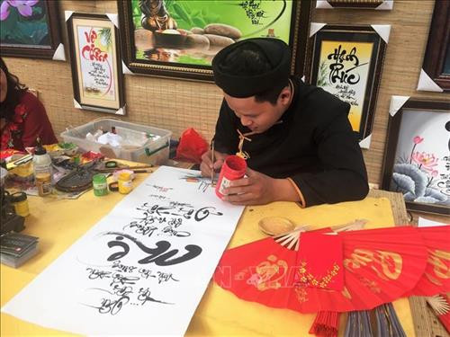 Ông đồ trẻ trong trang phục áo dài dân tộc chăm chút cho tác phẩm mừng Xuân Kỷ Hợi 2019. Ảnh: Gia Thuận - TTXVN Ông đồ trẻ trong trang phục áo dài dân tộc chăm chút cho tác phẩm mừng Xuân Kỷ Hợi 2019. Ảnh: Gia Thuận - TTXVN