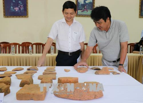 Các nhà nghiên cứu chia sẻ thông tin về những hiện vật được khai quật. Ảnh: Quốc Dũng – TTXVN