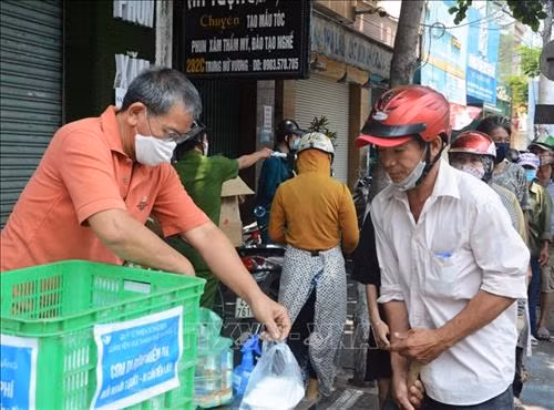 Nhóm thiện nguyện "Quán cơm yên vui" phát cho người có hoàn cảnh khó khăn. Ảnh: Văn Dũng - TTXVN
