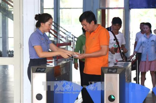 Hướng dẫn hành khách tại cổng soát vé tự động. Ảnh: Trần Xuân Tình-TTXVN