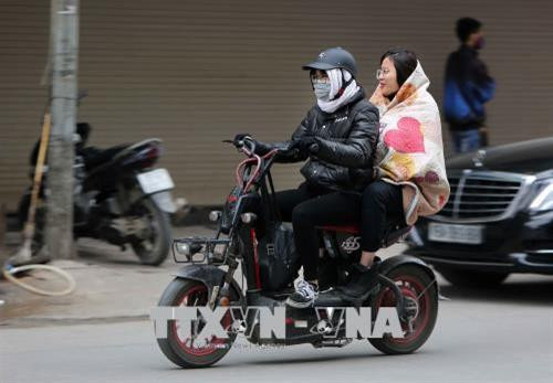 Người dân đắp cả chăn khi ra đường để tránh rét. Ảnh: Thành Đạt-TTXVN