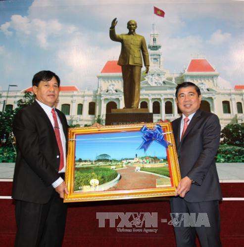 Lãnh đạo đoàn đại biểu 3 tỉnh Trung Lào tặng quà Chủ tịch UBND Thành phố Hồ Chí Minh Nguyễn Thành Phong. Ảnh: Thanh Vũ – TTXVN