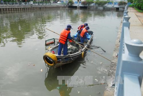 Nhân viên Môi trường đô thị thành phố vớt cá chết dọc hai bên bờ kênh Nhiêu Lộc - Thị Nghè. Ảnh: Mạnh Linh – TTXVN.