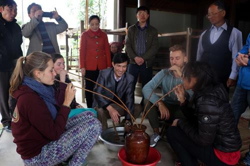 Du khách chung uống rượu cần với bà con dân tộc Thái. Ảnh: Bích Huệ - TTXVN