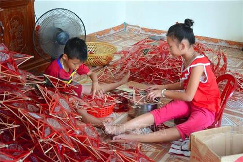 Không chỉ người lớn mà cả những đứa trẻ từ 7-8 tuổi tại làng Báo Đáp cũng tham gia làm đèn. Ảnh: Công Luật - TTXVN