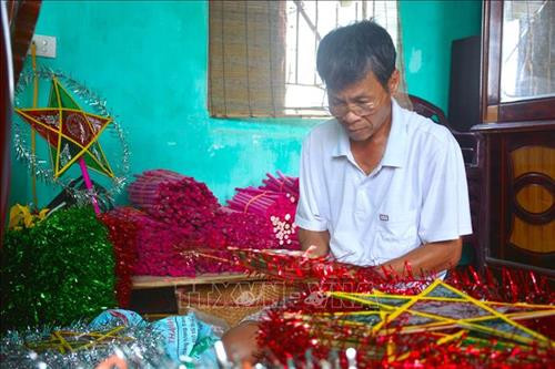 Ông Nguyễn Minh Đăng, một hộ chuyên làm đèn ông sao có tiếng trong làng Báo Đáp, đang làm loại đèn nhỏ. Ảnh: Công Luật - TTXVN