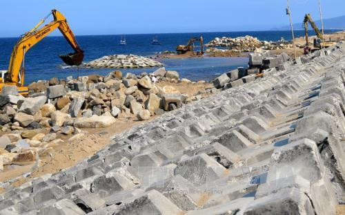 Nhà thầu vừa tổ chức thi công mái kè vừa thực hiện thi công các mỏ hàn ngoài bờ biển để ngăn nước biển xâm thực. Ảnh: Thế Lập – TTXVN.