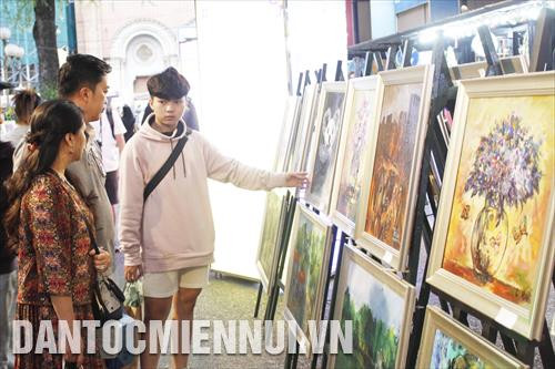 Khách tham quan xem tranh của các họa sĩ khuyết tật trưng bày tại triển lãm