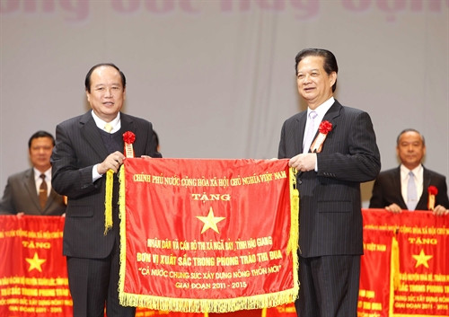 Thủ tướng Nguyễn Tấn Dũng, Chủ tịch Hội đồng thi đua khen thưởng Trung ương trao Cờ thi đua của Chính phủ cho các đơn vị xuất sắc trong phong trào thi đua “Cả nước chung sức xây dựng nông thôn mới”. Ảnh: Đức Tám – TTXVN