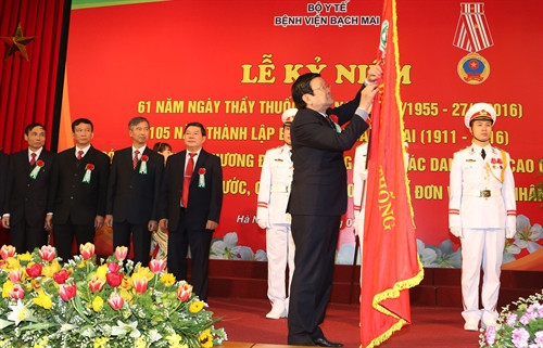 Chủ tịch nước Trương Tấn Sang gắn Huân chương Độc Lập hạng Ba lên lá cờ truyền thống của Bệnh viện Bạch Mai. Ảnh: Nguyễn Khang – TTXVN