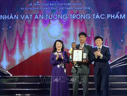 Đồng chí Hồ Quang Lợi, Phó Chủ tịch Thường trực Hội Nhà báo Việt Nam cùng Thứ trưởng Bộ Giáo dục và Đào tạo Nguyễn Thị Nghĩa trao giải Nhân vật tiêu biểu trong tác phẩm đoạt giải cho thầy giáo Đặng Văn Cương. Ảnh: Thanh Tùng-TTXVN