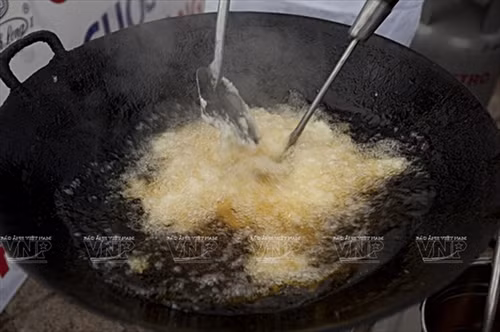 Xôi chín được đưa vào chảo chiên (rán).