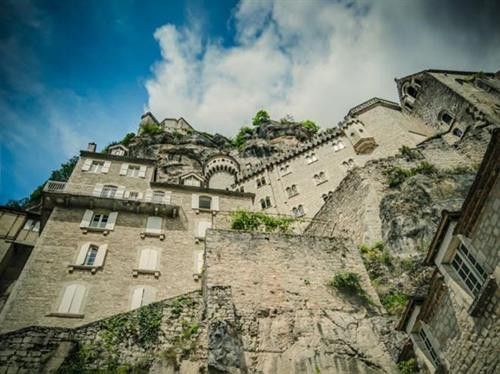 Ngôi làng cổ Rocamadour được xây dựng trên vách núi ở vùng Occitanie, miền tây nam Pháp. Từ thời Trung cổ, ngôi làng đã thu hút những người hành hương từ khắp châu Âu tới đây tham quan các công trình lịch sử và nhà thờ Đức Mẹ Maria. Thánh St Amator đã sống và qua đời tại ngôi làng Rocamadour ngay sau khi ông rời khỏi Jerusalem. Truyền thuyết kể rằng sau khi thi thể thánh St Amator được phát hiện, một số phép màu đã xảy ra. Ngôi làng bắt đầu thu hút nhiều người hành hương và ủng hộ từ các nhà vua Pháp, giúp ngôi làng xây dựng các nơi thờ cúng. Một lý do khác khiến Rocamadour thu hút nhiều du khách là phong cảnh đẹp. Các công trình cổ được xây dựng trên vách núi nhìn xuống sông Alzou. Các tòa nhà trong làng có độ cao cách mặt đất phía dưới khoảng 120m. Trung tâm của ngôi làng là nhà thờ hành hương Notre Dame, được cải tạo lại từ công trình gốc được xây dựng từ năm 1479. Ngoài ra, Rocamadour còn có nhiều công trình cổ kính khác được xây dựng từ thời Trung cổ. Du khách tham quan dọc một con đường dốc tại ngôi làng cổ Rocamadour. Những ngôi nhà được xây dựng trên vách đá dựng đứng. Ngôi làng cổ Rocamadour được xây dựng trên vách núi ở vùng Occitanie, miền tây nam Pháp. Từ thời Trung cổ, ngôi làng đã thu hút những người hành hương từ khắp châu Âu tới đây tham quan các công trình lịch sử và nhà thờ Đức Mẹ Maria. Thánh St Amator đã sống và qua đời tại ngôi làng Rocamadour ngay sau khi ông rời khỏi Jerusalem. Truyền thuyết kể rằng sau khi thi thể thánh St Amator được phát hiện, một số phép màu đã xảy ra. Ngôi làng bắt đầu thu hút nhiều người hành hương và ủng hộ từ các nhà vua Pháp, giúp ngôi làng xây dựng các nơi thờ cúng. Một lý do khác khiến Rocamadour thu hút nhiều du khách là phong cảnh đẹp. Các công trình cổ được xây dựng trên vách núi nhìn xuống sông Alzou. Các tòa nhà trong làng có độ cao cách mặt đất phía dưới khoảng 120m. Trung tâm của ngôi làng là nhà thờ hành hương Notre Dame, được cải tạo lại từ công trình gốc được xây dựng từ năm 1479. Ngoài ra, Rocamadour còn có nhiều công trình cổ kính khác được xây dựng từ thời Trung cổ. Du khách tham quan dọc một con đường dốc tại ngôi làng cổ Rocamadour. Những ngôi nhà được xây dựng trên vách đá dựng đứng.