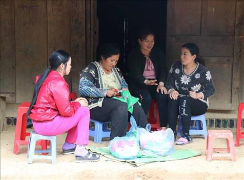 Bên hiên nhà, những người phụ nữ dân tộc Mông miệt mài với công việc thêu thùa, may vá chuẩn bị trang phục mới đón Tết. Ảnh: Xuân Tiến - TTXVN