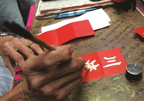 Chữ "Đón xuân" được viết bằng ngọn bút lông, mực nhũ kim trên nền giấy đỏ tẩm hương