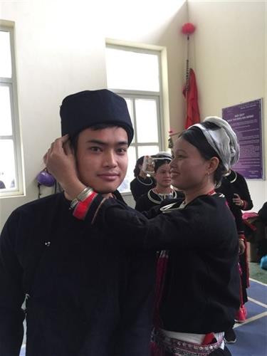 Các cô gái dân tộc Sán Chỉ giúp bạn nam vấn lại khăn, chính sừa trang phục cùng nhau vui hội.