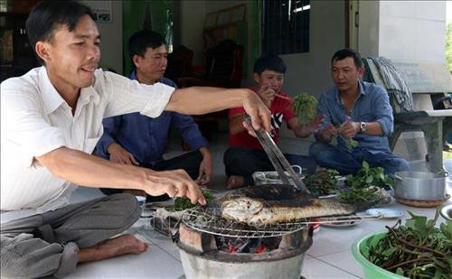 Du khách thưởng thức cá nướng, rau rừng tự bắt và hái tại Tiểu khu rừng tràm 34. Ảnh: Lê Sen - TTXVN