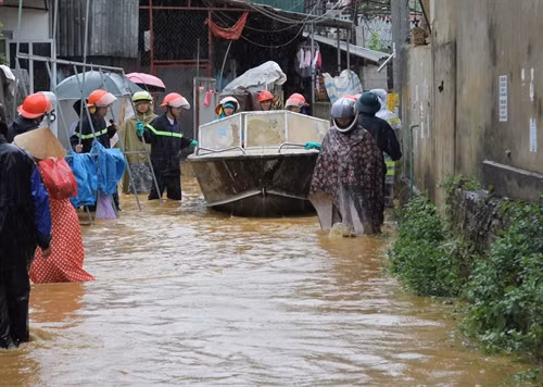 Lực lượng chức năng dùng xuồng sắt giúp bà con di chuyển đồ đạc khỏi vùng bị ngập. Ảnh: Quang Duy- TTXVN