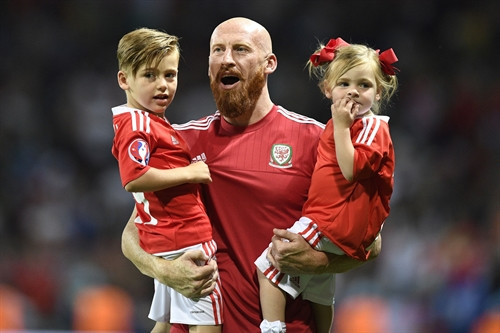 Trong ảnh:Hậu vệ James Collins của Xứ Wales mừng chiến thắng với các con sau trận đấu. AFP/TTXVN