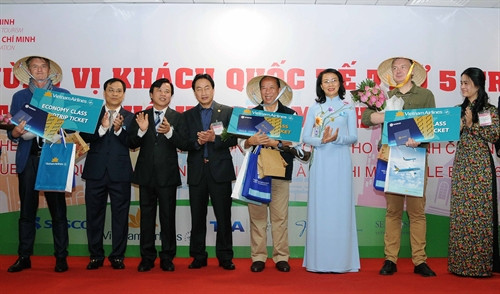 Lãnh đạo Thành phố tặng quà cho vị khách thứ 5 triệu và hai vị khách liền kề đi trên chuyến bay VN10 từ Pháp đến Tp. Hồ Chí Minh. Ảnh: An Hiếu – TTXVN