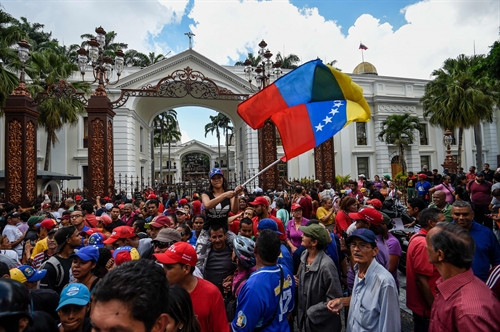 Những người ủng hộ Tổng thống Venezuela Nicolas Maduro tuần hành bên ngoài tòa nhà Quốc hội vào thời điểm các nghị sĩ của phe đối lập đang tiến hành phiên họp tại Caracas ngày 23/10. AFP/TTXVN