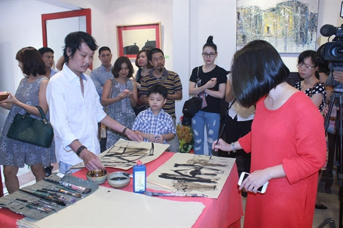 Họa sĩ Phạm Trần Quân và họa sĩ Phương Bình vẽ trên chất liệu giấy dó.