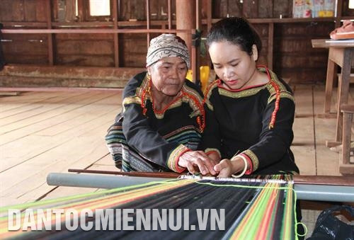 Bà H’Ngăng Niê hướng dẫn em H’et Niê cách tạo ra hoa văn trên tấm thổ cẩm. Ảnh: Phạm Cường