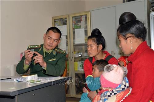 Cán bộ quân y Đồn Biên phòng Phiêng Pằn hướng dẫn người dân sử dụng thuốc. Ảnh: Hữu Quyết - TTXVN