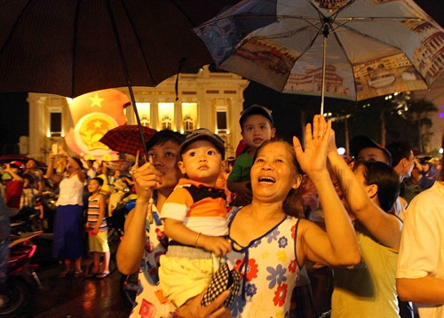 Người dân đội mưa xem bắn pháo hoa tại hồ Hoàn Kiếm, Hà Nội. Ảnh: TTXVN