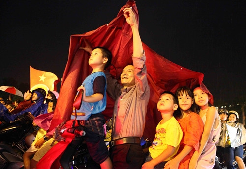 Mặc dù thời tiết không thuận lợi nhưng đông đảo người dân vẫn đội mưa xem bắn pháo hoa tại hồ Hoàn Kiếm, Hà Nội. Ảnh: TTXVN