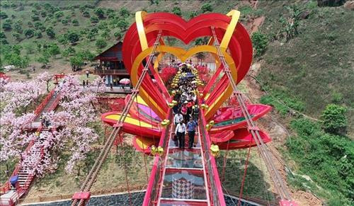 Du khách tham quan và trải nghiệm cầu kính tình yêu tại Khu du lịch sinh thái thác Dải Yếm, huyện Mộc Châu, tỉnh Sơn La. Ảnh: TTXVN