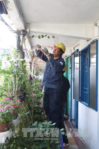 Đoàn viên thanh niên lắp đặt, sửa chữa điện miễn phí cho người dân tại chung cư Tôn Thất Thuyết (Quận 4). Ảnh: Thanh Vũ - TTXVN.