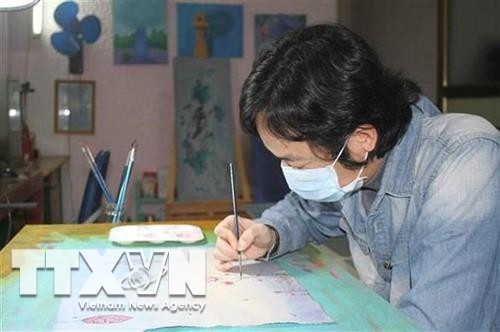 Họa sỹ Phan Tuấn Ngọc vẽ tranh với chủ đề "Hãy ở nhà". Ảnh: Thùy Dung - TTXVN